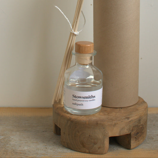 Stowsmiths diffuser set with bottle, sticks, and cardboard tube on a wooden stand.